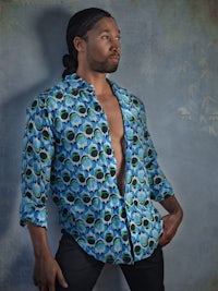 a man in a blue shirt posing against a wall